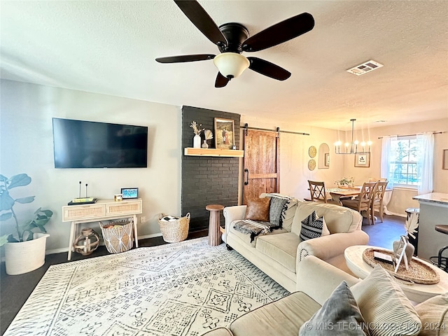 living room featuring a textured ceiling, a barn door, and ceiling fan with notable chandelier