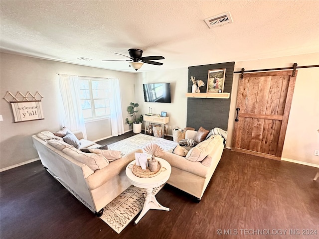 living room with dark hardwood / wood-style flooring, a barn door, a textured ceiling, and ceiling fan