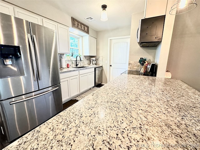 kitchen with appliances with stainless steel finishes, white cabinetry, and light stone counters