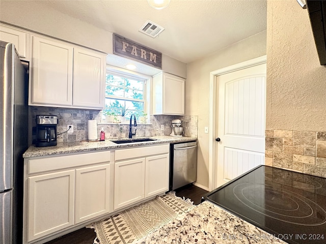 kitchen featuring backsplash, white cabinets, sink, light stone counters, and stainless steel appliances