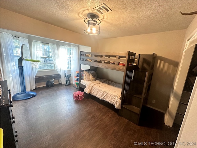 bedroom with dark hardwood / wood-style floors and a textured ceiling