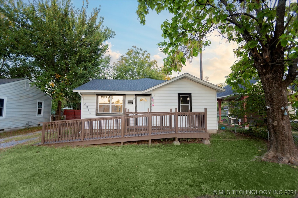 back house at dusk with a deck and a yard