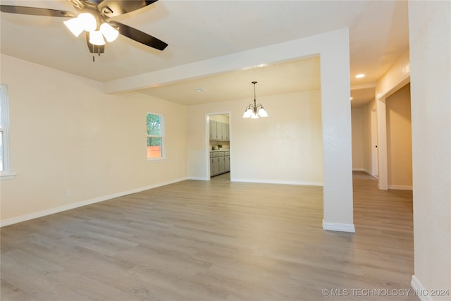 unfurnished room featuring ceiling fan with notable chandelier and light hardwood / wood-style flooring