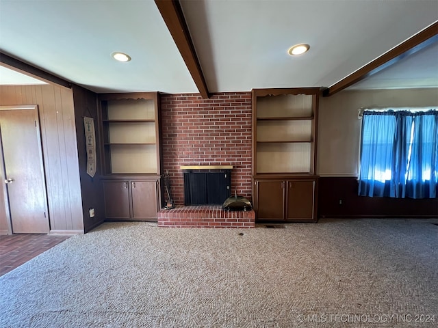 unfurnished living room with beamed ceiling, built in shelves, and a brick fireplace