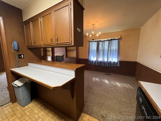 kitchen featuring kitchen peninsula, light colored carpet, pendant lighting, an inviting chandelier, and wood walls