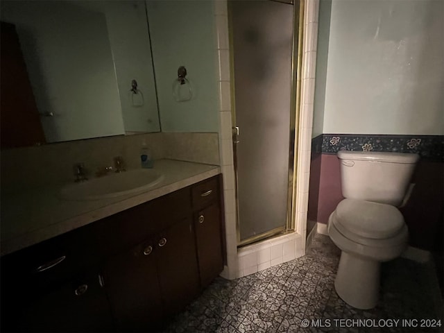 bathroom featuring tile patterned floors, vanity, toilet, and a shower with door