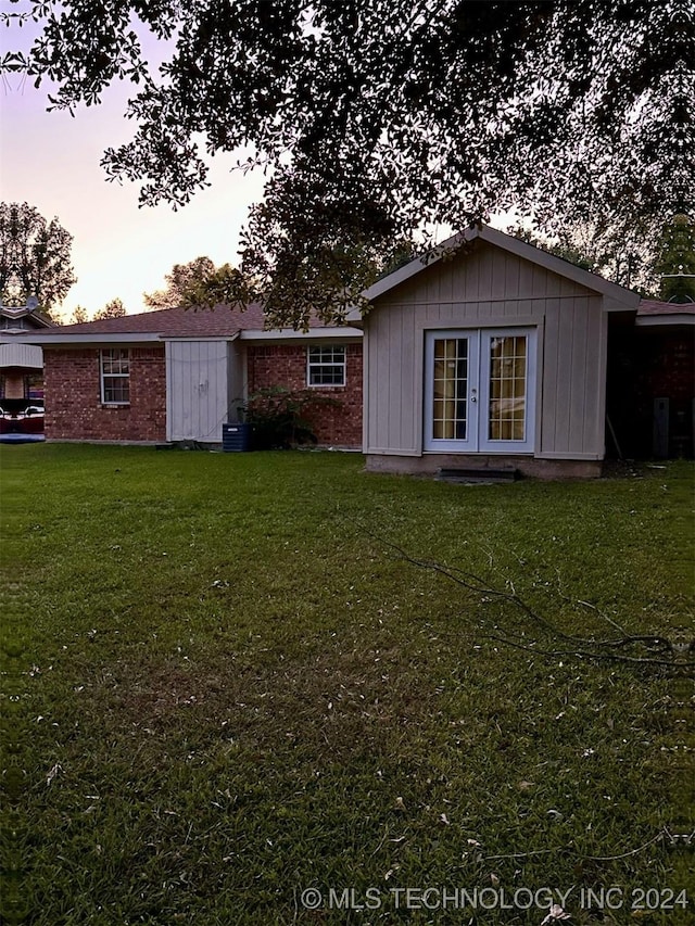 back house at dusk with a lawn