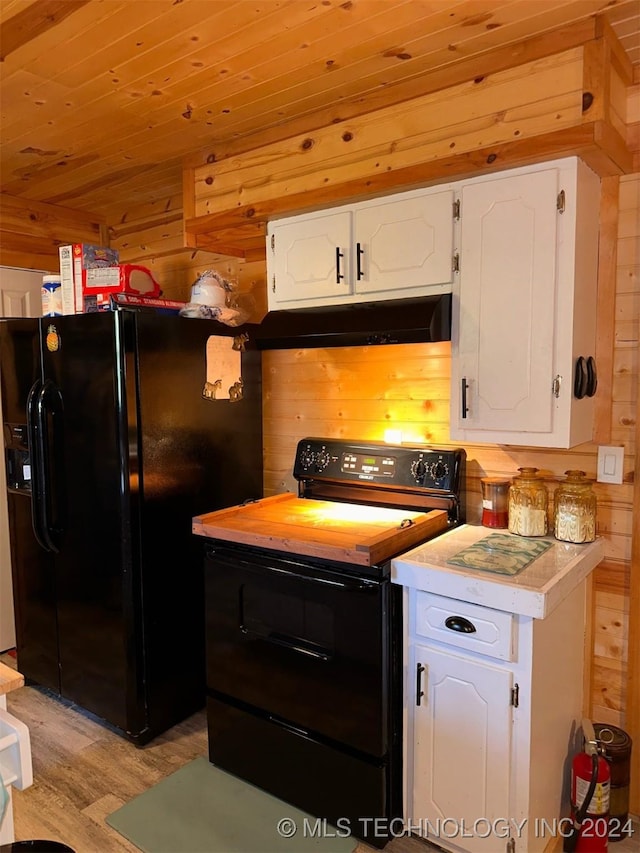 kitchen featuring black appliances, white cabinetry, wooden walls, and light hardwood / wood-style flooring