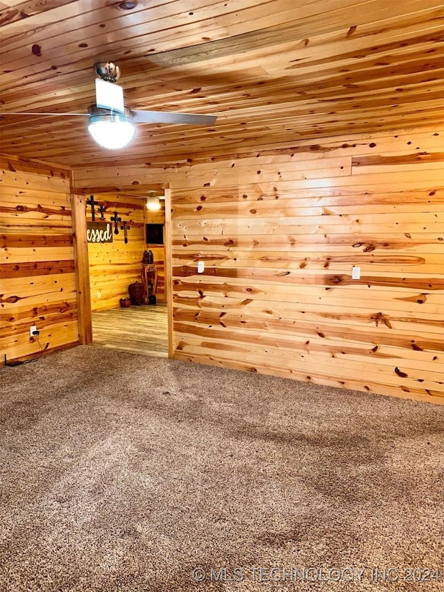 empty room featuring wooden walls, carpet floors, and wooden ceiling