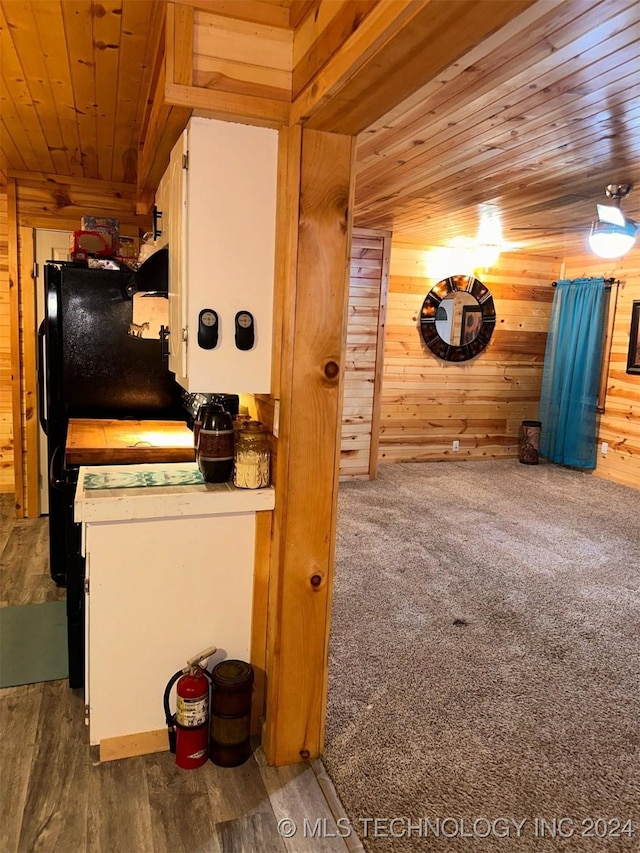 kitchen with wood walls, wood-type flooring, wood ceiling, and white cabinetry