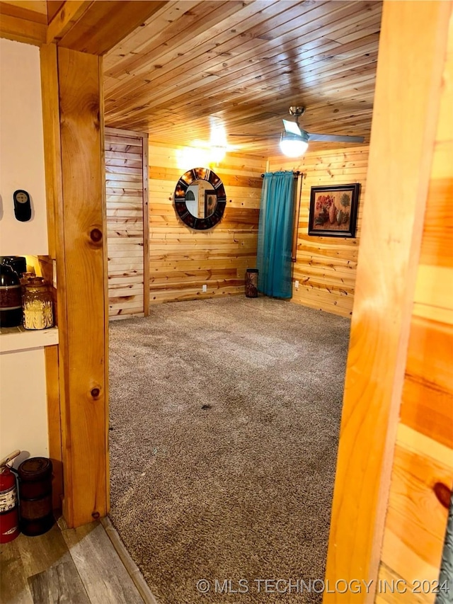 interior space with carpet flooring, wooden ceiling, and wooden walls