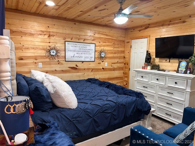 carpeted bedroom with ceiling fan, wooden walls, and wood ceiling