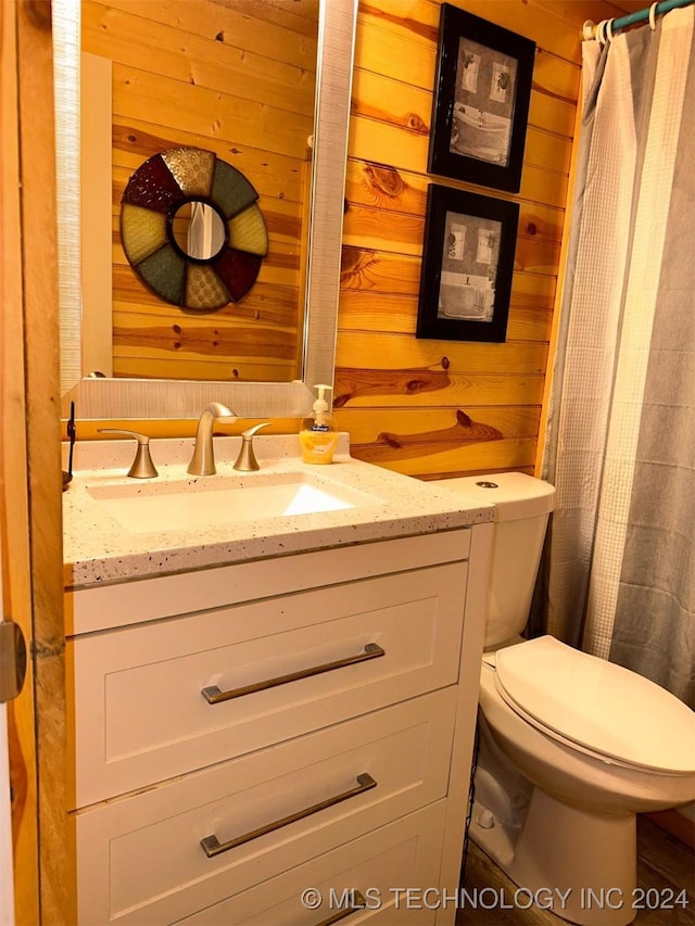 bathroom featuring walk in shower, wood walls, vanity, and toilet