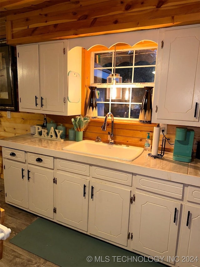 kitchen featuring white cabinets, wood walls, dark hardwood / wood-style flooring, and sink