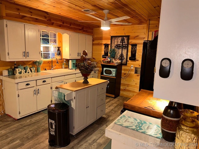 kitchen with ceiling fan, sink, white cabinets, and wooden walls