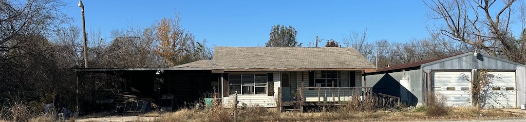 view of front of home with a garage, covered porch, and an outdoor structure