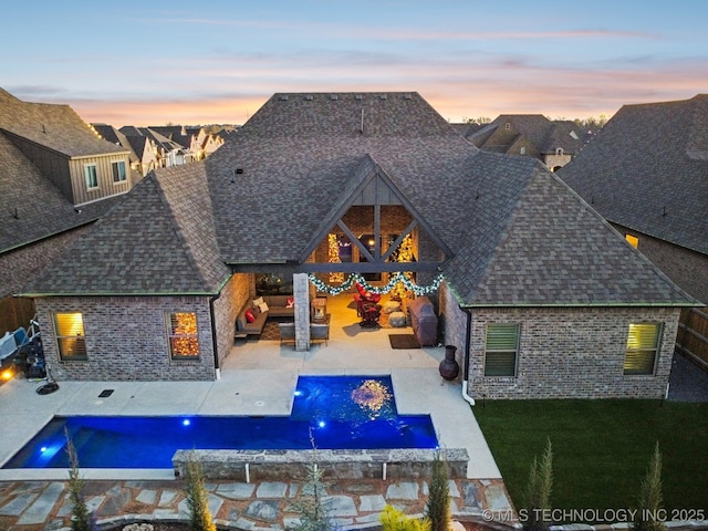 back house at dusk featuring a pool with hot tub, pool water feature, a patio area, and outdoor lounge area