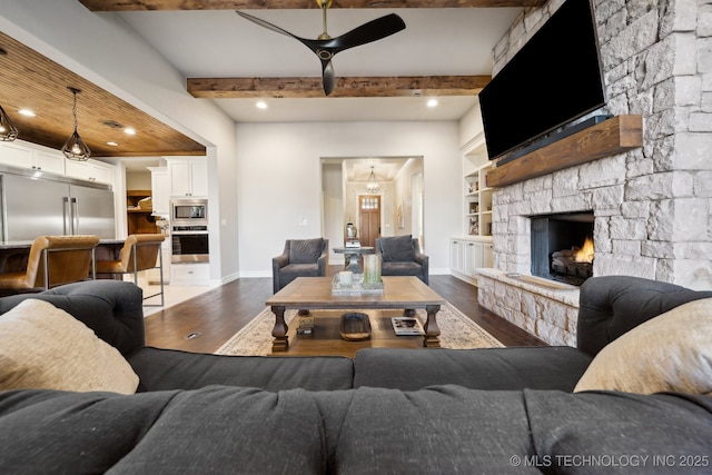 living room featuring wood-type flooring, a fireplace, built in shelves, and beamed ceiling