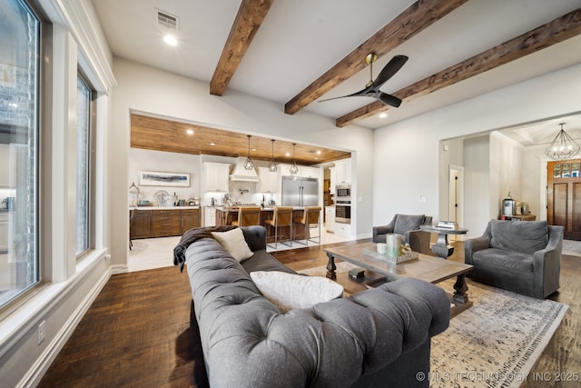 living room with beam ceiling, dark wood-type flooring, and ceiling fan with notable chandelier