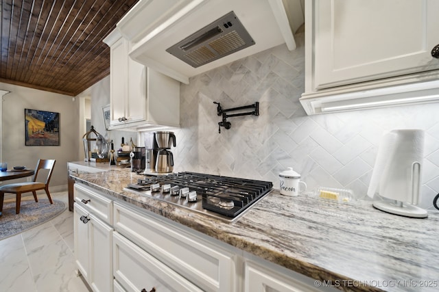 kitchen with white cabinets, custom exhaust hood, stainless steel gas stovetop, light stone countertops, and wood ceiling