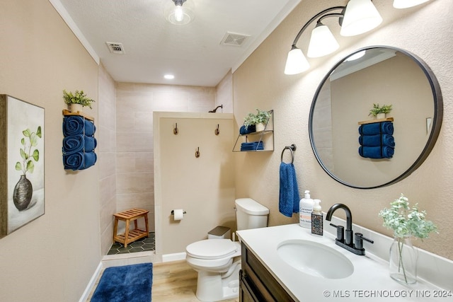 bathroom featuring tiled shower, toilet, vanity, and hardwood / wood-style flooring