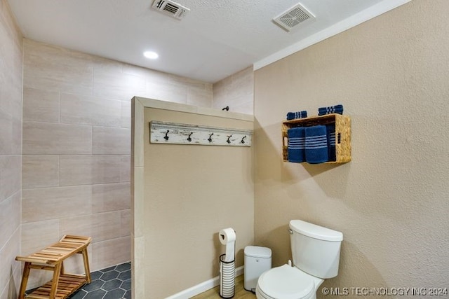 bathroom featuring toilet, a shower, and tile walls