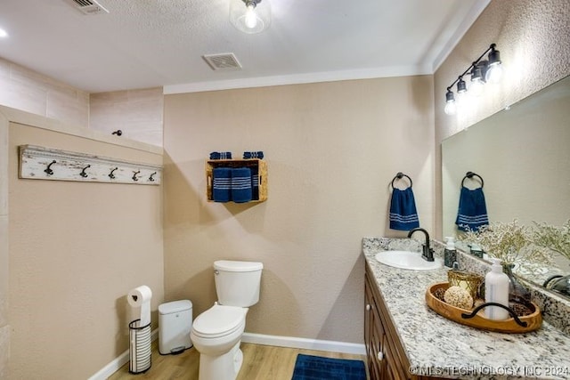 bathroom featuring a textured ceiling, vanity, hardwood / wood-style flooring, and toilet