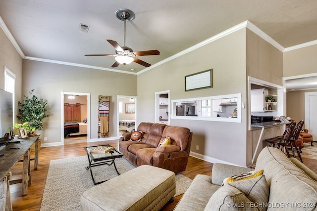 living room with hardwood / wood-style floors, ceiling fan, a towering ceiling, and crown molding