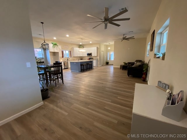 living room featuring ceiling fan with notable chandelier and dark wood-type flooring