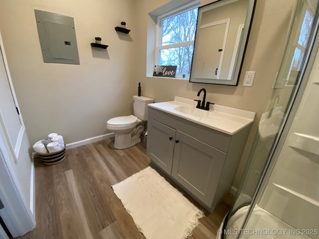 bathroom with vanity, a shower with door, wood-type flooring, electric panel, and toilet