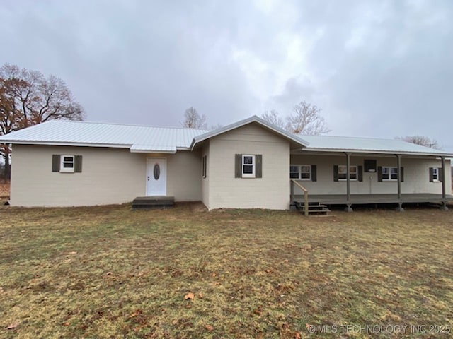 ranch-style house with metal roof, a yard, and concrete block siding