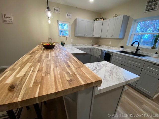 kitchen featuring pendant lighting, wood counters, gray cabinetry, and sink