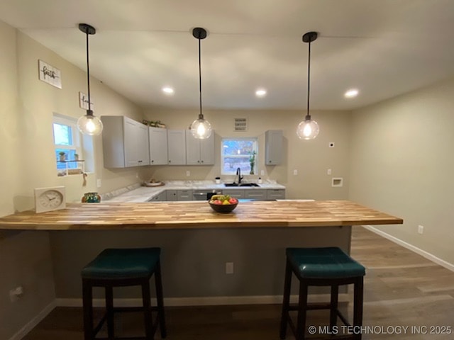 bar with butcher block countertops, dark hardwood / wood-style flooring, sink, and hanging light fixtures