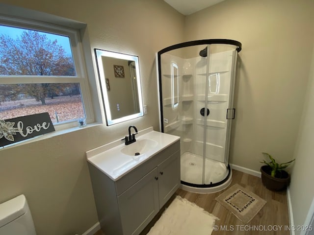 full bathroom with toilet, a stall shower, vanity, wood finished floors, and plenty of natural light