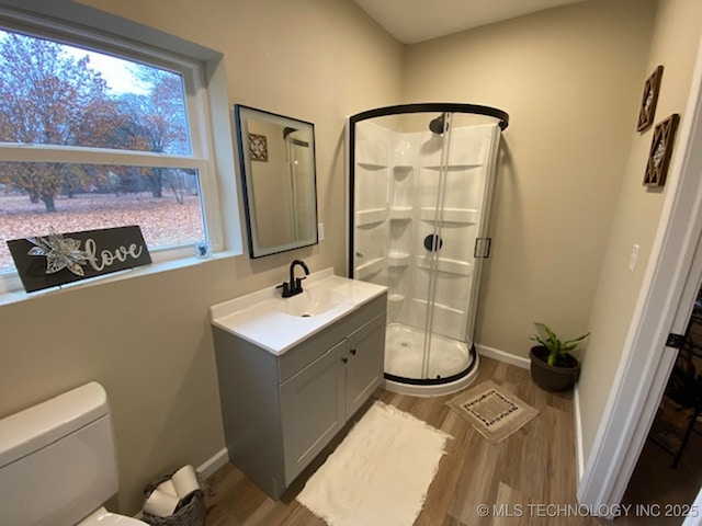 bathroom with hardwood / wood-style floors, vanity, toilet, and a shower with shower door