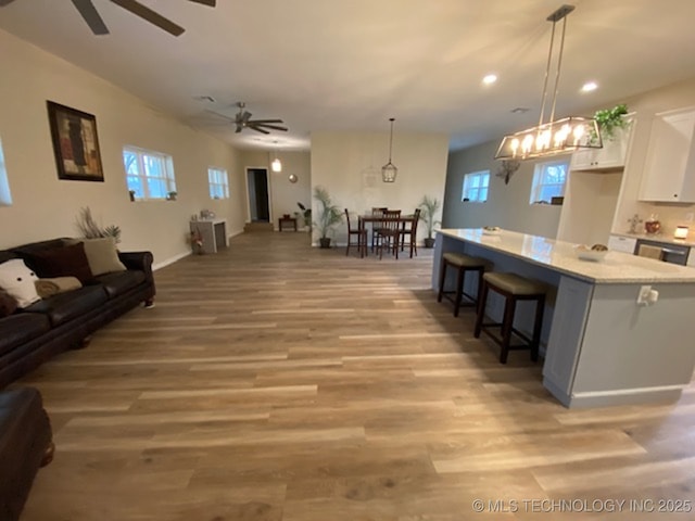 kitchen with open floor plan, decorative light fixtures, white cabinetry, and a kitchen breakfast bar