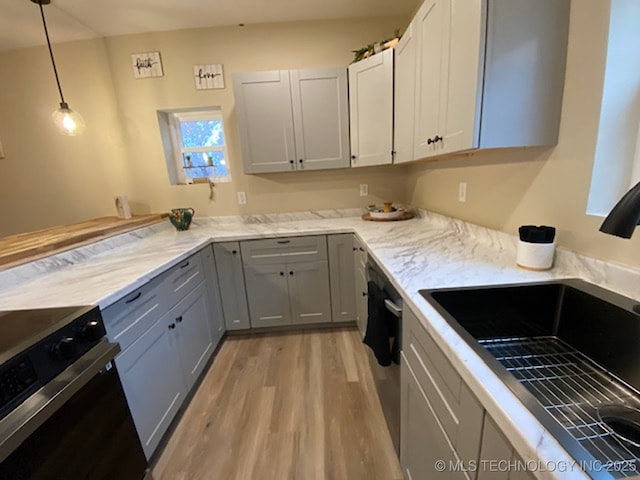 kitchen featuring gray cabinetry, stainless steel appliances, sink, decorative light fixtures, and light hardwood / wood-style floors