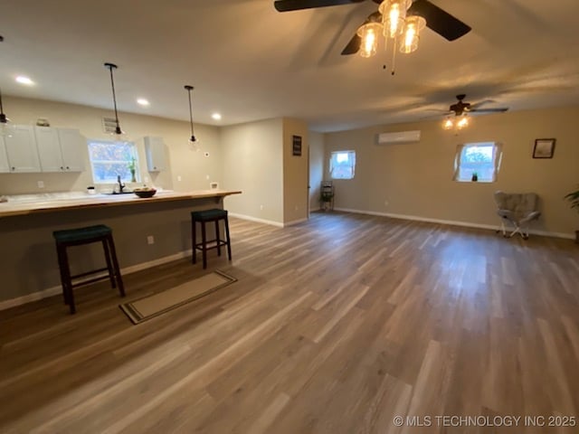 kitchen featuring white cabinetry, ceiling fan, dark hardwood / wood-style floors, decorative light fixtures, and a breakfast bar