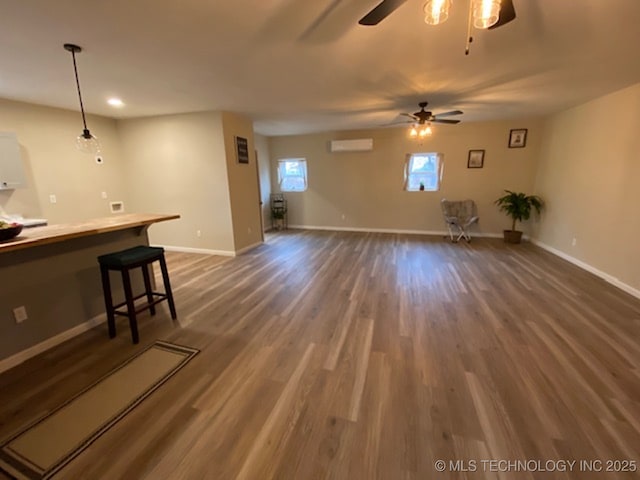 unfurnished living room featuring dark wood-type flooring, ceiling fan, and baseboards