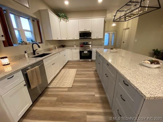 kitchen with stainless steel appliances, sink, hanging light fixtures, and white cabinets