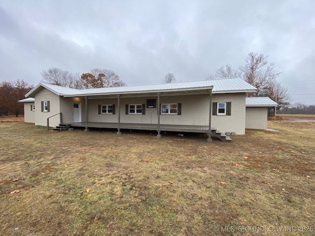 back of house with metal roof and a lawn