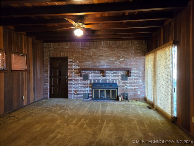 unfurnished living room with beamed ceiling, carpet floors, and wooden walls