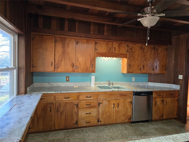 kitchen featuring dishwasher, sink, wooden walls, ceiling fan, and beamed ceiling