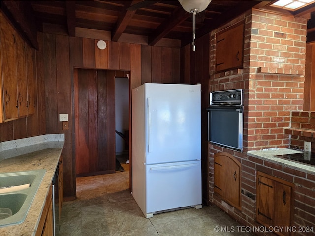 kitchen featuring wood walls, wooden ceiling, black appliances, sink, and beam ceiling