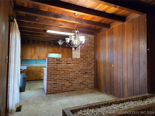 unfurnished dining area featuring beamed ceiling, wood walls, a notable chandelier, and wood ceiling