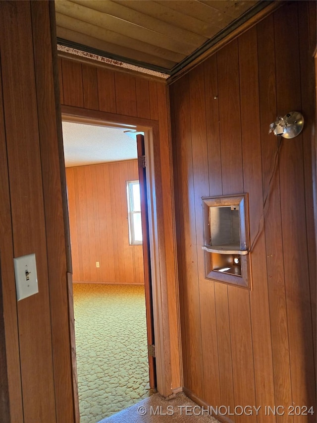 corridor featuring wooden walls, carpet floors, and wooden ceiling