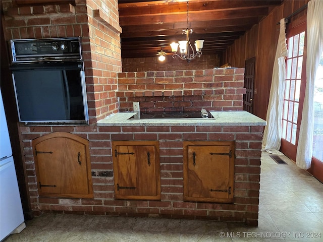 kitchen featuring wooden ceiling, black appliances, hanging light fixtures, wooden walls, and a notable chandelier