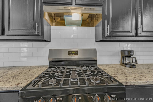 kitchen with gas stove, light stone counters, exhaust hood, and tasteful backsplash