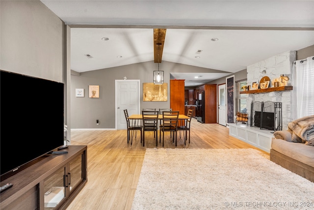 dining space with vaulted ceiling with beams, light hardwood / wood-style floors, and a fireplace