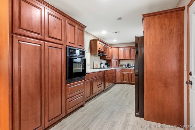 kitchen featuring decorative backsplash, light hardwood / wood-style flooring, and black appliances